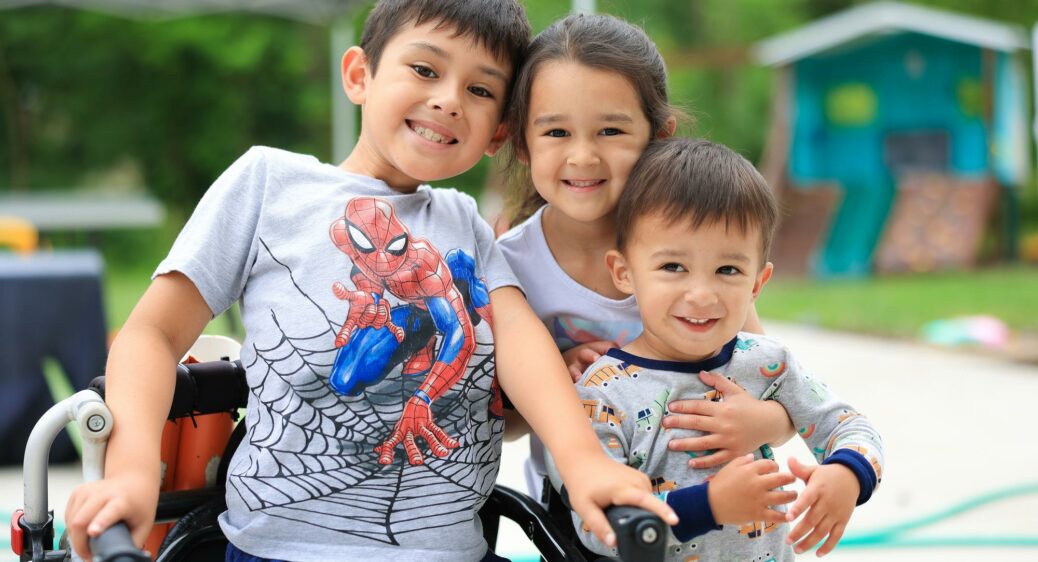 3 young siblings smiling and posing for a picture